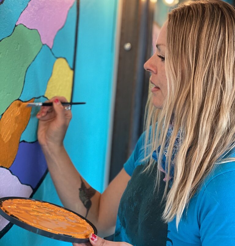 Desirée Rosborg painting a butterfly mural